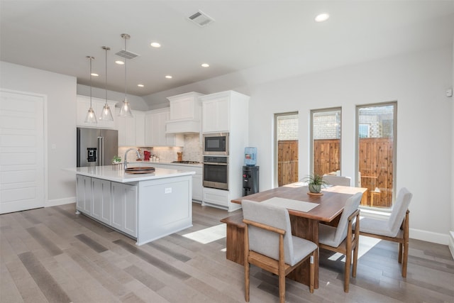 kitchen featuring appliances with stainless steel finishes, white cabinetry, visible vents, and decorative backsplash