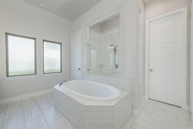 full bathroom with a tile shower, a garden tub, and baseboards