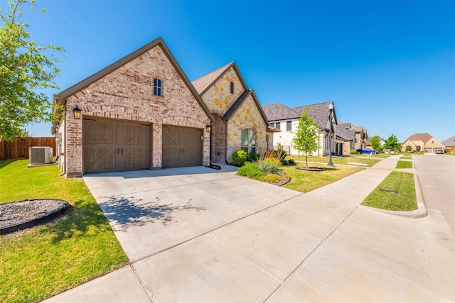 french country style house with driveway, fence, a front lawn, central AC, and brick siding