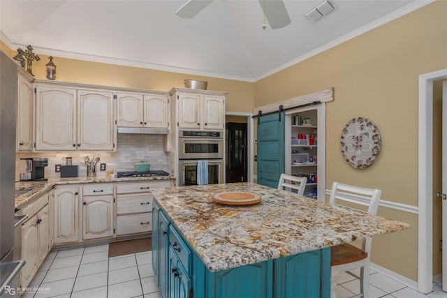 kitchen featuring light tile patterned floors, a barn door, visible vents, decorative backsplash, and under cabinet range hood