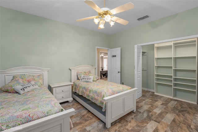 bedroom with baseboards, visible vents, a ceiling fan, stone finish flooring, and a closet