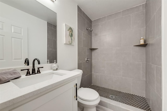 bathroom with tiled shower, vanity, and toilet