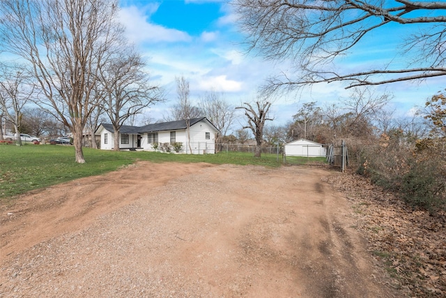 exterior space featuring dirt driveway, a front yard, and fence