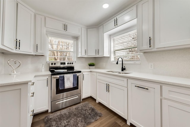 kitchen featuring electric range, dark wood-type flooring, a sink, and white cabinetry