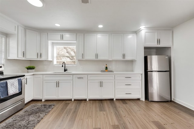 kitchen featuring white cabinetry, stainless steel appliances, a sink, and light countertops