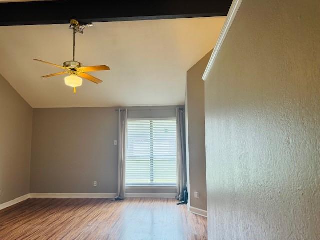 unfurnished room with lofted ceiling, wood finished floors, a ceiling fan, and baseboards