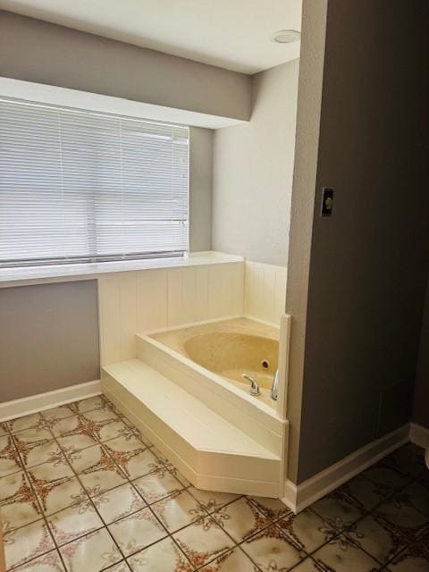 bathroom featuring a garden tub and baseboards