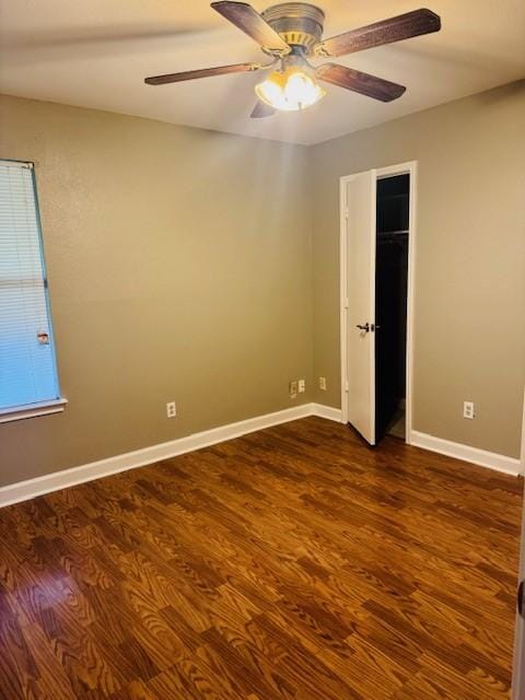 spare room with ceiling fan, baseboards, and dark wood-type flooring