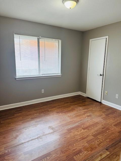 spare room with wood finished floors and baseboards