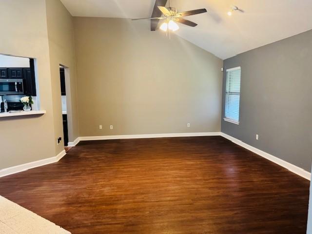 spare room featuring a ceiling fan, high vaulted ceiling, baseboards, and wood finished floors