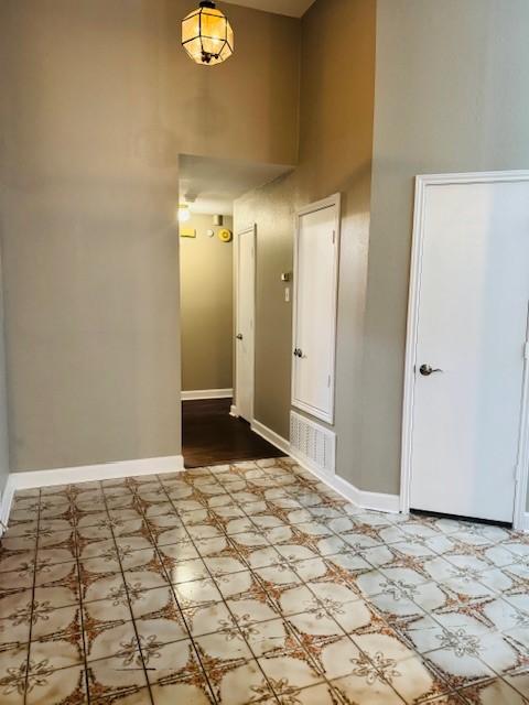 foyer featuring a high ceiling, baseboards, and tile patterned floors