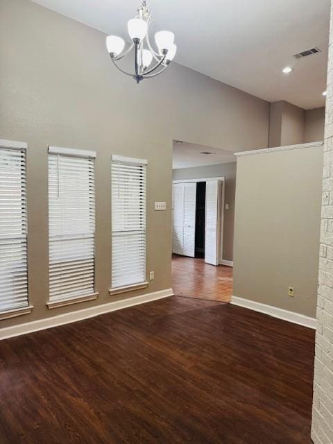 empty room featuring a notable chandelier, wood finished floors, and baseboards