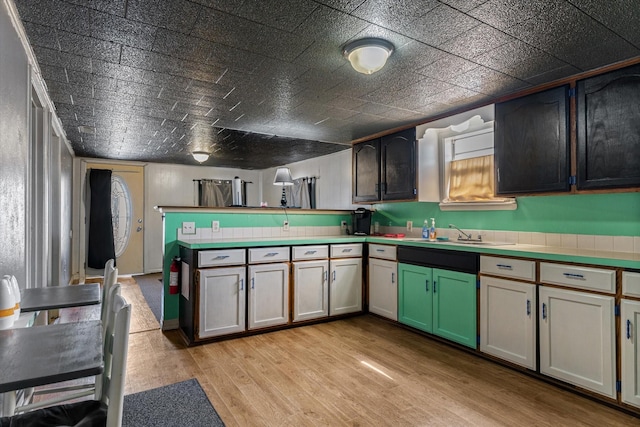 kitchen featuring a peninsula, light wood-type flooring, and a sink