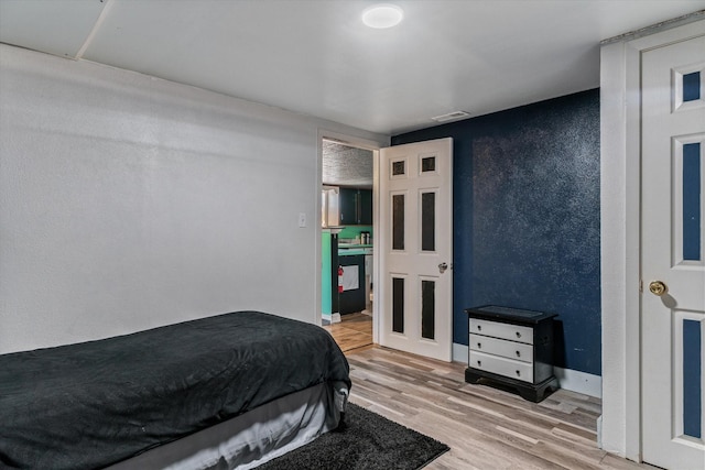 bedroom with visible vents, a textured wall, and wood finished floors