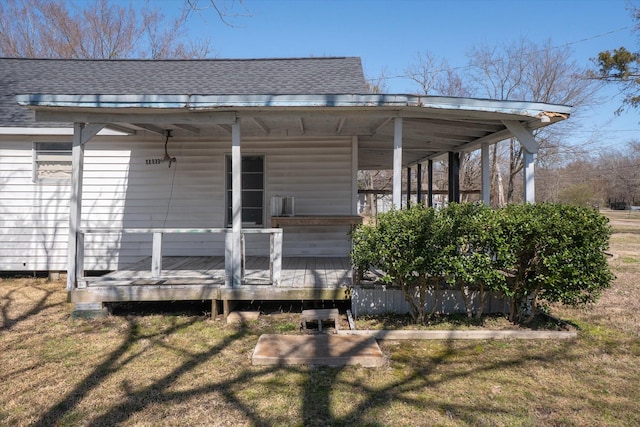 back of property with roof with shingles and a lawn