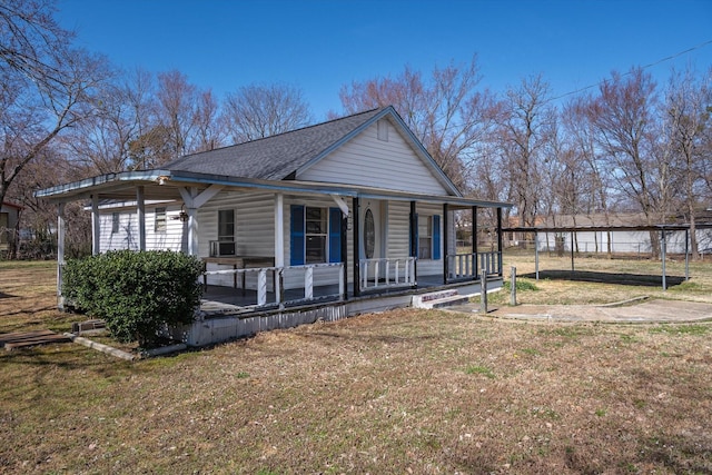 view of front of house featuring covered porch, roof with shingles, fence, and a front lawn