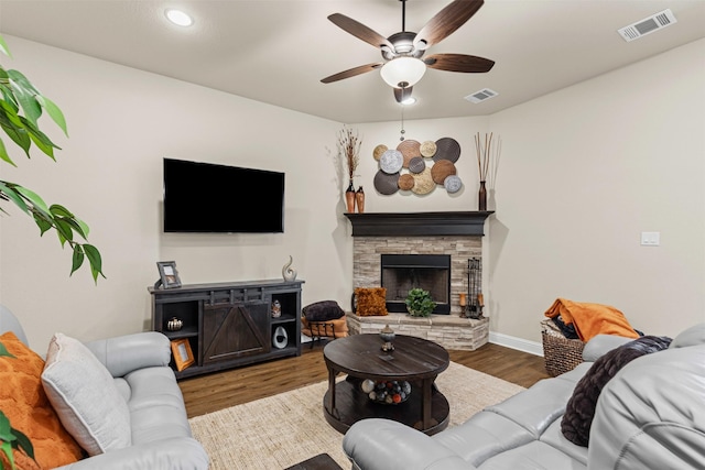 living area featuring a ceiling fan, visible vents, a fireplace, and wood finished floors