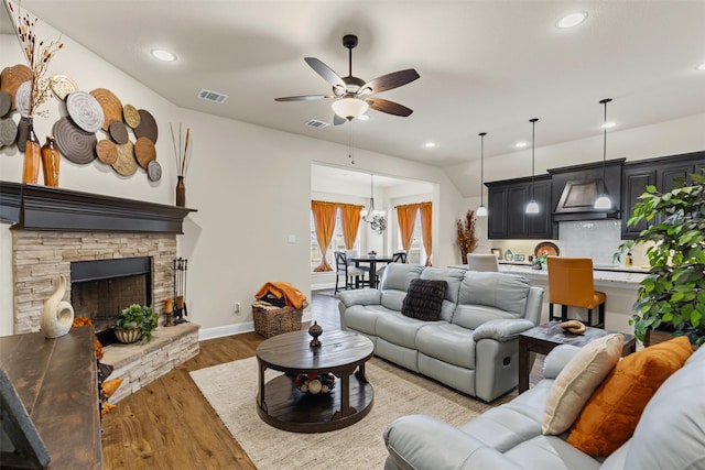 living room with baseboards, visible vents, wood finished floors, a fireplace, and recessed lighting