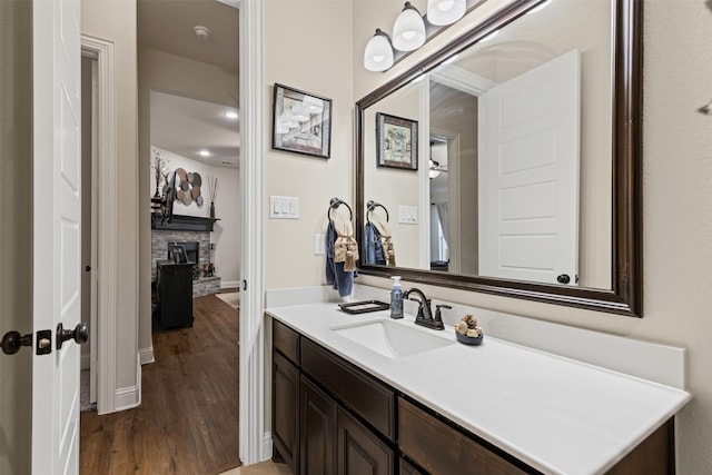 bathroom with a fireplace, vanity, baseboards, and wood finished floors