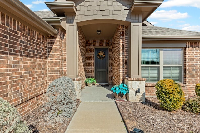 property entrance featuring brick siding and roof with shingles