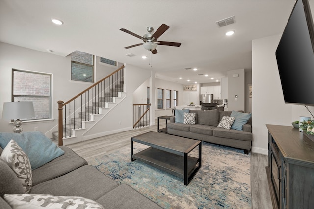 living room with light wood-type flooring, stairs, visible vents, and recessed lighting