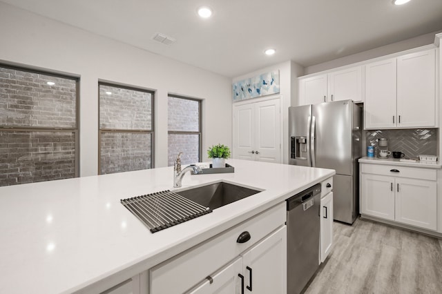 kitchen featuring light countertops, appliances with stainless steel finishes, a sink, and white cabinets