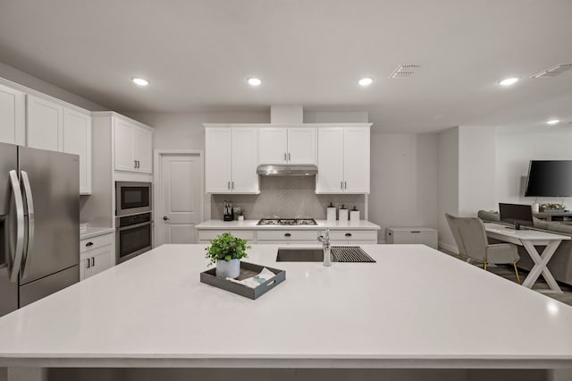 kitchen featuring under cabinet range hood, a sink, white cabinets, light countertops, and appliances with stainless steel finishes