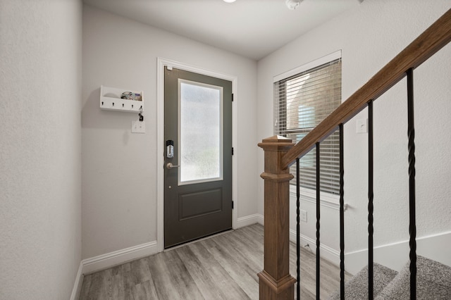 foyer entrance featuring stairway, baseboards, and wood finished floors