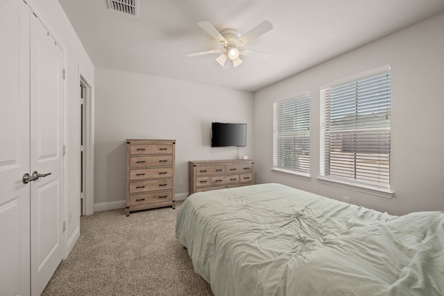 bedroom featuring a closet, light colored carpet, visible vents, ceiling fan, and baseboards