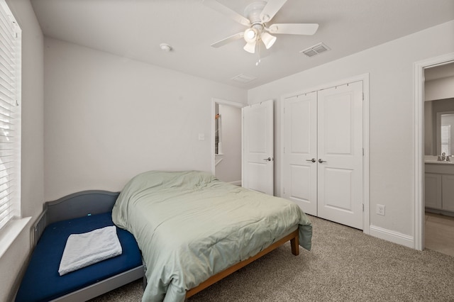 carpeted bedroom featuring a closet, visible vents, a ceiling fan, a sink, and baseboards