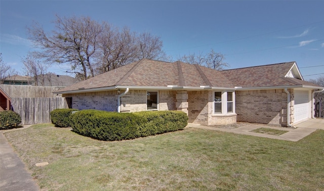 ranch-style home featuring brick siding, a shingled roof, fence, and a front yard