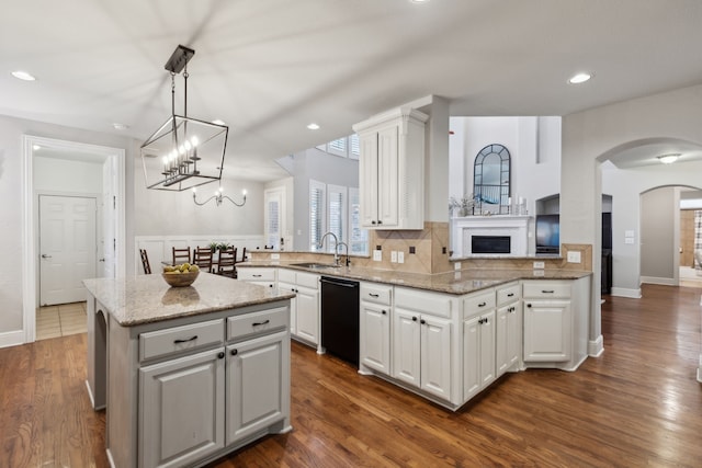 kitchen featuring a kitchen island, a sink, white cabinets, black dishwasher, and backsplash