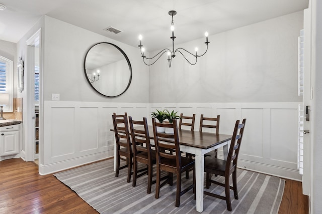 dining room featuring a wainscoted wall, visible vents, dark wood finished floors, and a chandelier