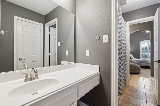 bathroom with visible vents, connected bathroom, a textured wall, tile patterned flooring, and vanity