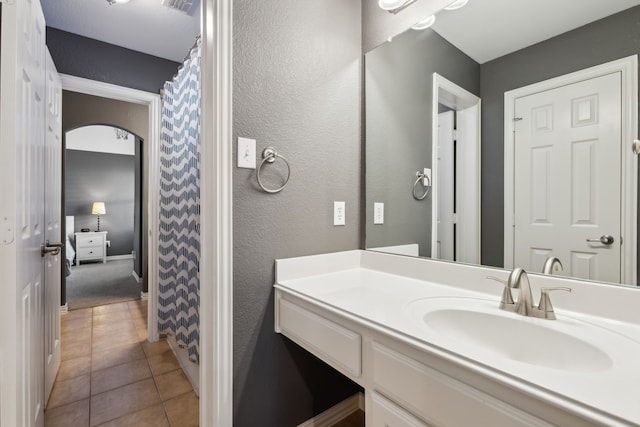 bathroom with tile patterned flooring, a textured wall, and vanity