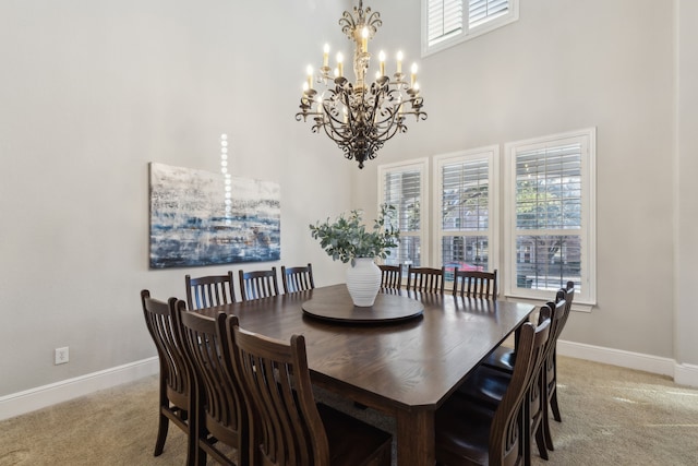 dining room featuring an inviting chandelier, a high ceiling, baseboards, and light colored carpet