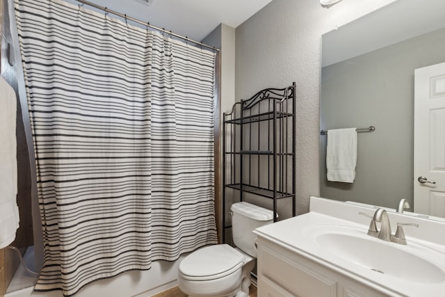 bathroom with shower / bath combo, a textured wall, vanity, and toilet