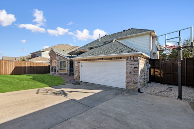 view of front of home with concrete driveway, roof with shingles, an attached garage, fence, and a front lawn