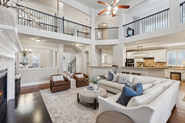 living area featuring arched walkways, dark wood-style flooring, a fireplace, baseboards, and stairway