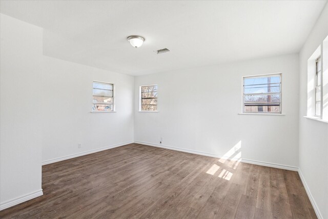 spare room featuring wood finished floors, visible vents, and baseboards