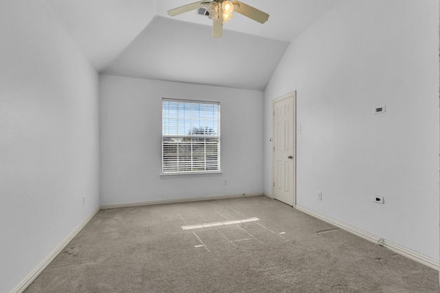 carpeted spare room featuring a ceiling fan, visible vents, vaulted ceiling, and baseboards