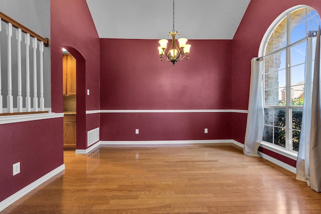 unfurnished dining area with vaulted ceiling, an inviting chandelier, visible vents, and light wood-style floors