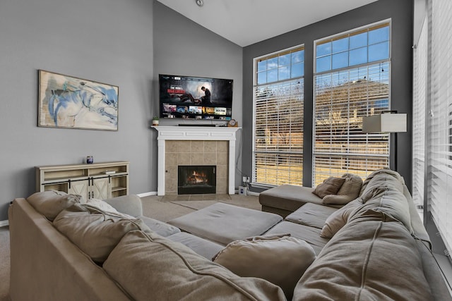 living room featuring baseboards, carpet flooring, vaulted ceiling, and a tiled fireplace