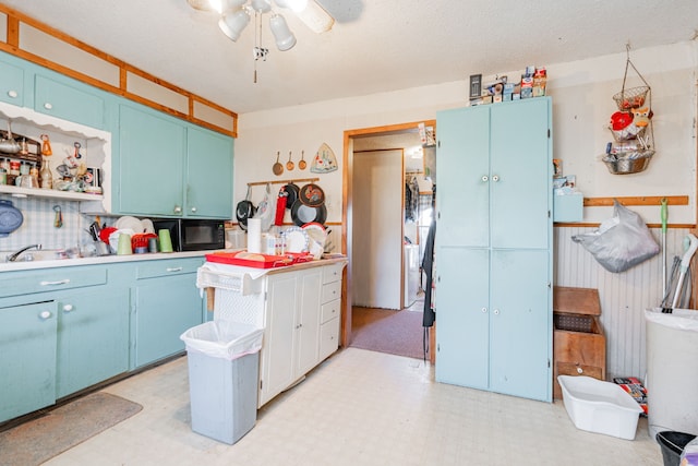 kitchen featuring blue cabinets, light floors, open shelves, and wainscoting