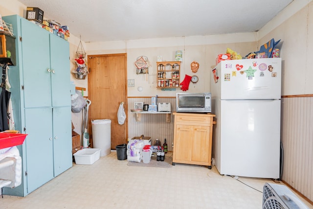 kitchen featuring freestanding refrigerator, stainless steel microwave, and tile patterned floors