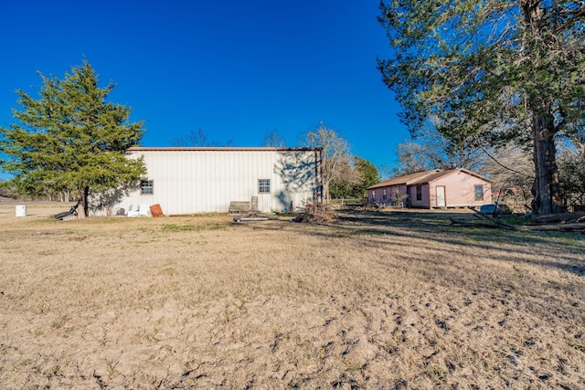 back of property featuring a pole building, a yard, and an outdoor structure