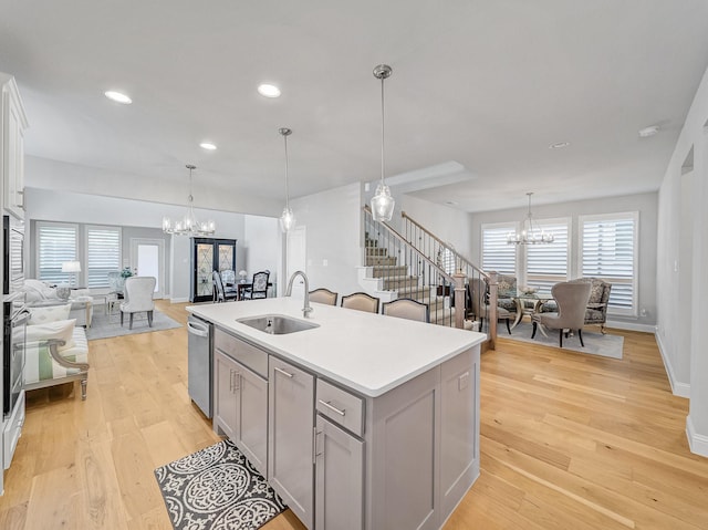 kitchen featuring gray cabinetry, a notable chandelier, open floor plan, and a sink