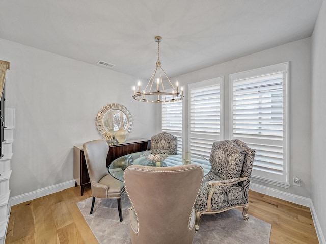 dining space with light wood-style floors, baseboards, visible vents, and a chandelier