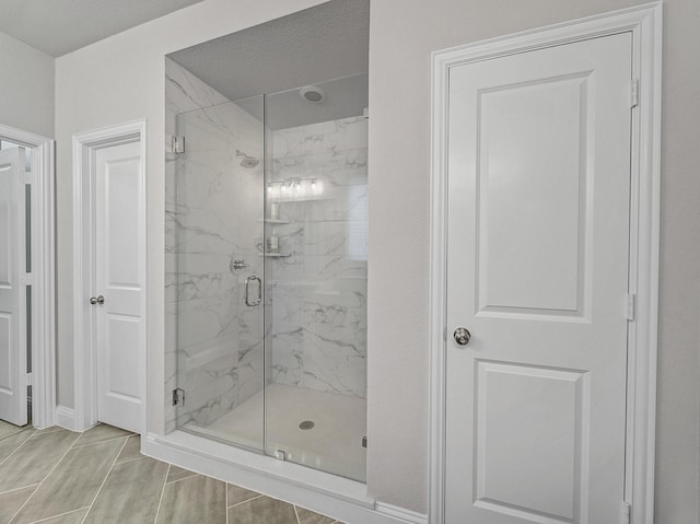 full bath with a marble finish shower and baseboards