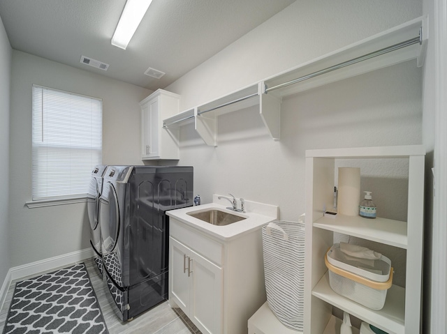 clothes washing area featuring cabinet space, visible vents, a sink, and independent washer and dryer